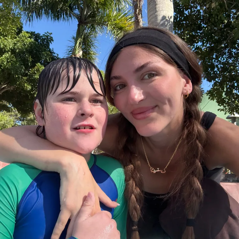 A participant and support worker sharing a hug outdoors
