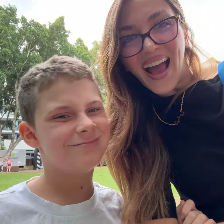 A support worker and young participant smiling together outdoors