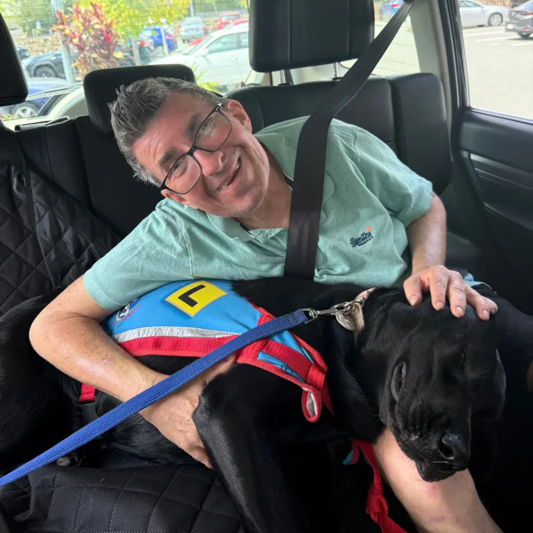 A participant smiling in the car beside a black dog
