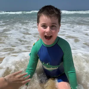 A young boy smiling in the ocean waves