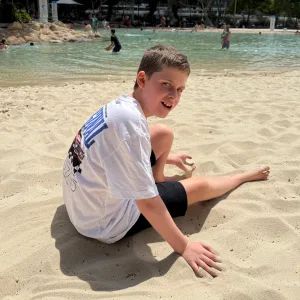 A young participant smiling while playing in the sand at the beach