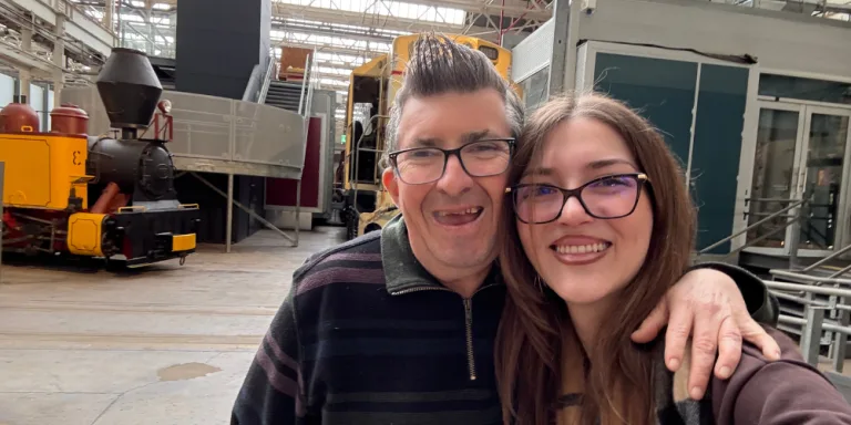 A participant and support worker smiling together on an outing