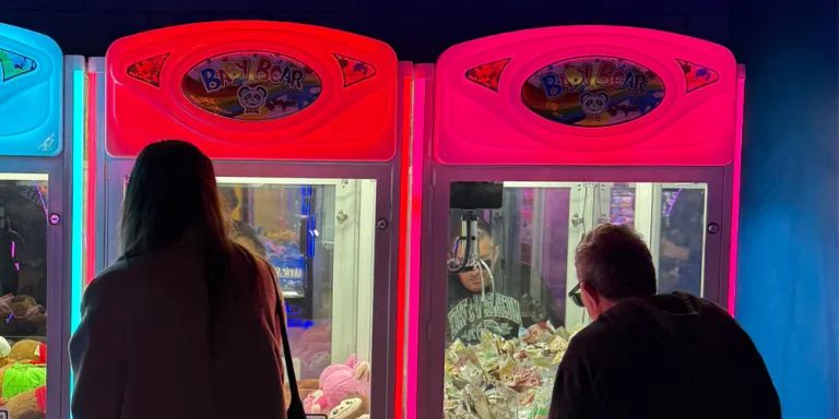 A participant and support worker playing arcade games together