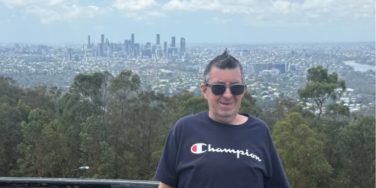 A participant at a lookout with a city skyline behind him